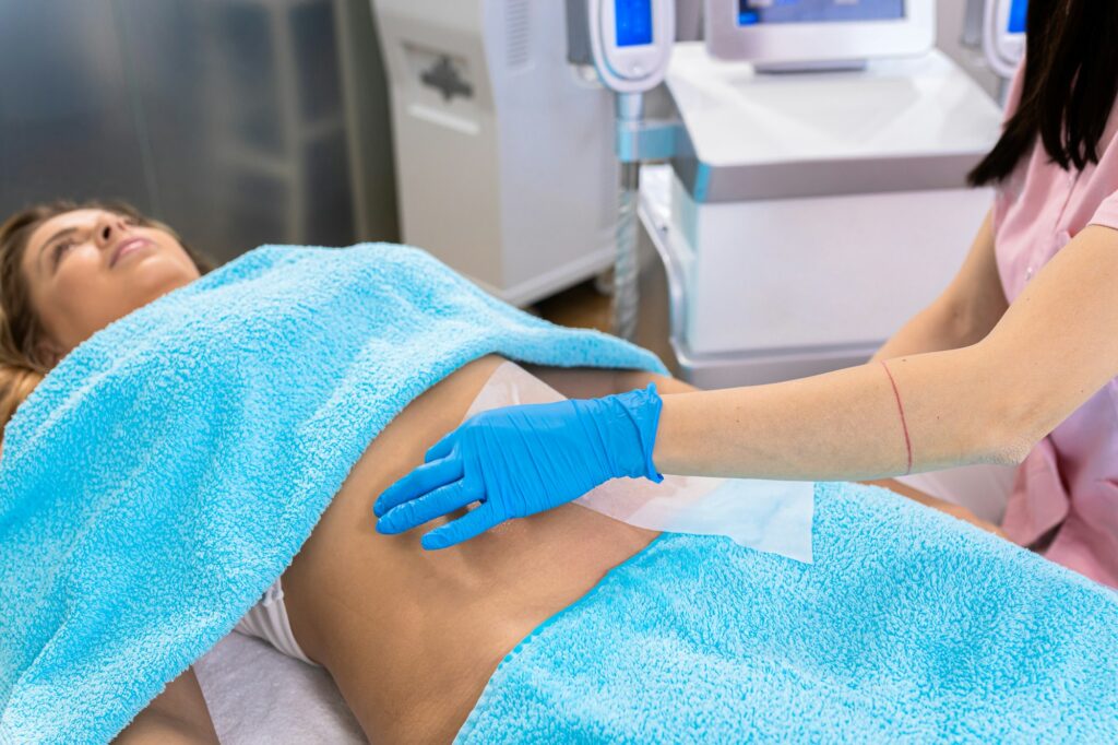 Beautician therapist applying cryolipolysis treatment in beauty salon